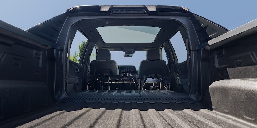 The back of a black truck showing the interior with seats folded down.